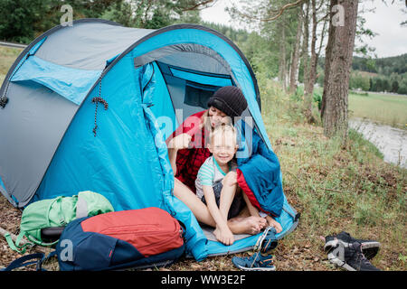 Portrait de mère et fils souriant serrant dans une tente tout en camping Banque D'Images