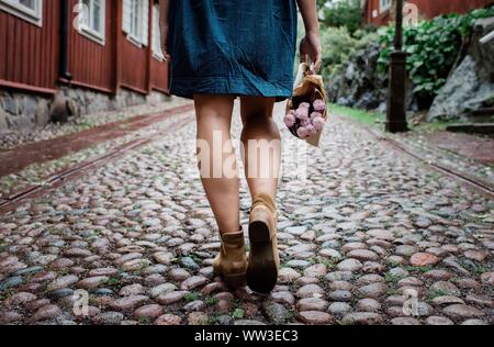 Les femmes jambes marche sur une rue pavée holding Flowers Banque D'Images