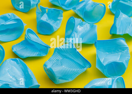 Détail de tasses jetables en plastique bleu cassé sur un fond jaune. Banque D'Images