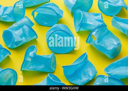 Détail de tasses jetables en plastique bleu cassé sur un fond jaune. Banque D'Images