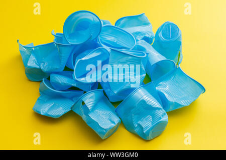 Détail de tasses jetables en plastique bleu cassé sur un fond jaune. Banque D'Images