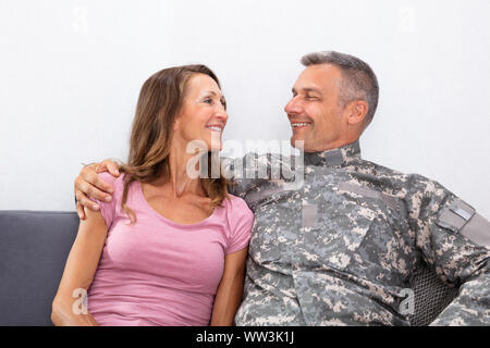 Soldat souriant avec sa femme assis sur un canapé et regarder Banque D'Images