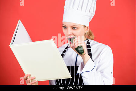 Mon travail. femme dans cook hat et tablier. Femme au foyer avec livre de cuisine. menu du restaurant. Suivre un régime culinaire. chef professionnel dans la cuisine manger du concombre. Cuisine. happy woman la cuisson des aliments sains par recette. Banque D'Images