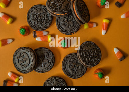 Les cookies au chocolat d'halloween avec une crème orange centre rempli de bonbons et de maïs bonbons citrouilles peu regardant close up sur un fond orange Banque D'Images