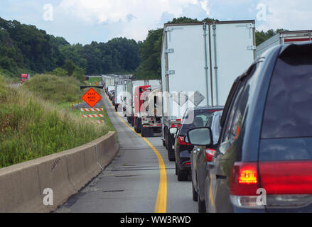 L'accent berline blanc coincé dans freeway traffic avec beaucoup d'autres grandes plates-formes et une quantité égale de voitures en raison de la construction de routes. Banque D'Images