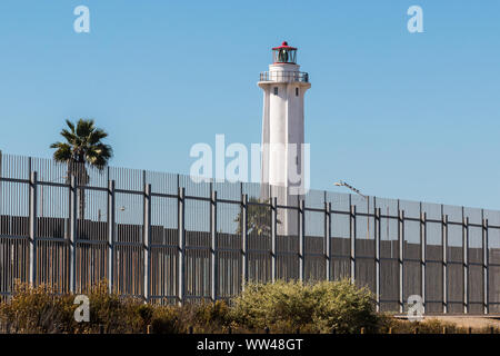 Clôture frontalière séparant San Diego, Californie et Tijuana, au Mexique, avec El Faro de Tijuana Mexique phare sur le côté. Banque D'Images