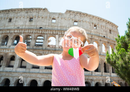 Drapeau Italien Girl Wearing Sunglasses, Holding Heart et Showing thumb up près de Colisée, Rome, Italie Banque D'Images