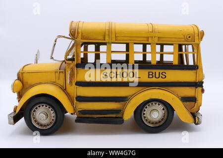 Gros plan d'un modèle de jouet d'autobus scolaire jaune vintage, vue de côté, isolé sur un fond blanc Banque D'Images