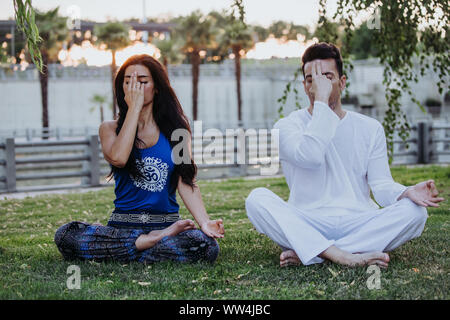 Homme de race blanche et femme latine méditer dans un parc de Madrid. La concentration et la détente en couple. Banque D'Images