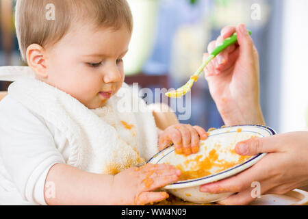 Sweet baby boy malpropre jouer avec la nourriture en mangeant. Banque D'Images