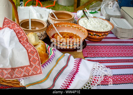 Pain à l'ail traditionnelle ukrainienne (pampushky) boulette et sauces (la crème, le beurre fondu, des oignons frits avec crépitements) dans l'argile po en céramique rustique Banque D'Images