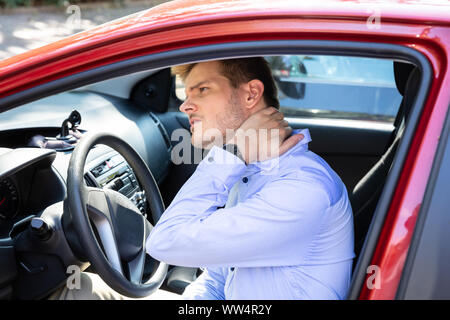 Driver Standing ayant la douleur au cou après Driving Car Banque D'Images