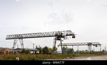 Deux grands portiques sur un site de construction, dans l'arrière-plan entrepôts industriels pour le stockage de marchandises. Type de roulement des structures métalliques de g Banque D'Images