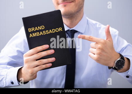 Man Holding livre avec texte et de pointage d'ambassadeur de la marque Banque D'Images