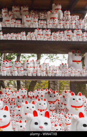 Un nombre de figurines Lucky Cat sur l'affichage sur le plateau dans un espace extérieur à Gotokuji Temple où l'chat est originaire, Tokyo, Japon. Banque D'Images