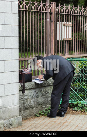 Un homme d'affaires japonais travaille à l'extérieur de la clôture du parc avec une manière inconfortable physiquement pendant les heures de travail à Tokyo, Japon. Banque D'Images