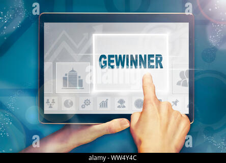 Une main holiding comprimé d'un ordinateur et en appuyant sur un 'Winner' Gewinner concept d'entreprise. Banque D'Images