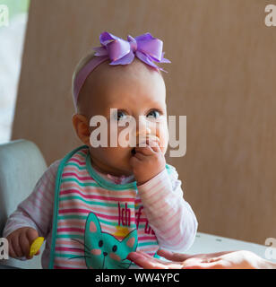 Le bébé mange à la table de ses mains Banque D'Images