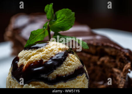 Balle jaune crème glace au chocolat avec garniture et tranche de gâteau au chocolat. Formant un dessert gastronomique. Banque D'Images