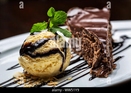 Balle jaune crème glace au chocolat avec garniture et tranche de gâteau au chocolat. Formant un dessert gastronomique. Banque D'Images