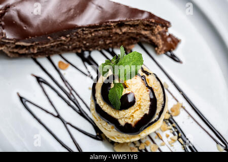 Balle jaune crème glace au chocolat avec garniture et tranche de gâteau au chocolat. Formant un dessert gastronomique. Banque D'Images