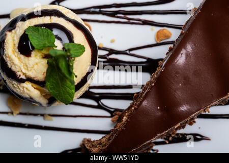 Balle jaune crème glace au chocolat avec garniture et tranche de gâteau au chocolat. Formant un dessert gastronomique. Vue de dessus. Banque D'Images