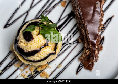 Balle jaune crème glace au chocolat avec garniture et tranche de gâteau au chocolat. Formant un dessert gastronomique. Banque D'Images
