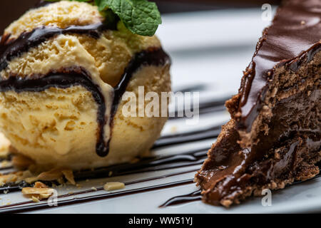 Balle jaune crème glace au chocolat avec garniture et tranche de gâteau au chocolat. Formant un dessert gastronomique. Banque D'Images