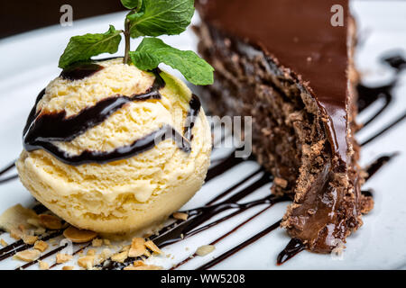 Balle jaune crème glace au chocolat avec garniture et tranche de gâteau au chocolat. Formant un dessert gastronomique. Banque D'Images