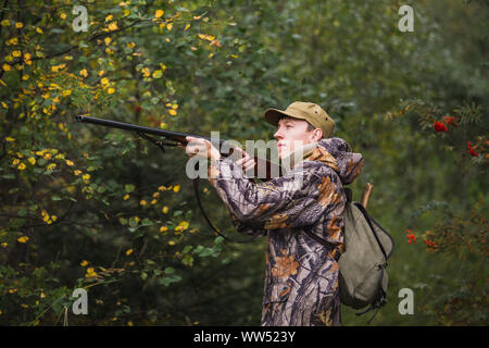 Hunter avec un sac à dos et un fusil de chasse dans la forêt d'automne. Banque D'Images