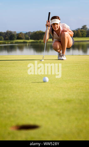 L'analyse de l'golfeur fille vert pour mettre la balle en tasse. Banque D'Images