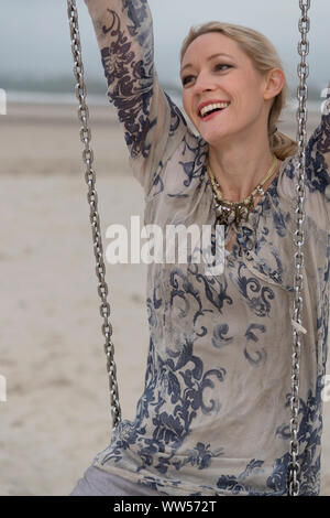 Femme assise sur swing sur la plage Banque D'Images