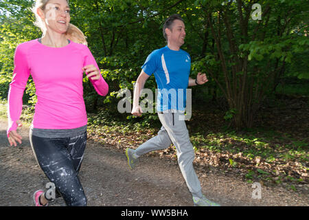 Couple jogging dans la forêt, le long de l'appareil photo Banque D'Images