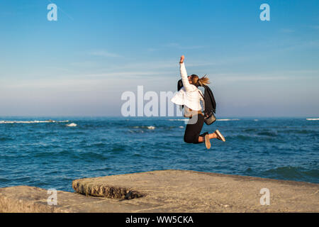 Femme sautant en l'air sur la plage, Italie Banque D'Images