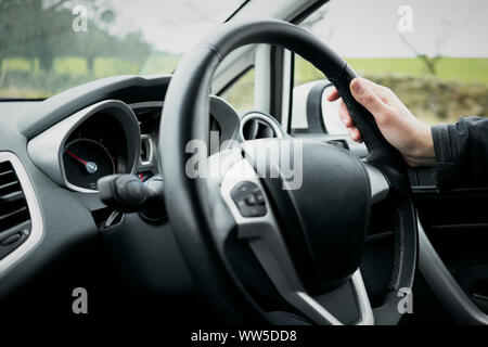 Une main de femme tenant un volant d'une voiture pendant la conduite. Banque D'Images