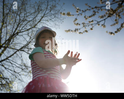 5-year-old fille en robe rayée rire debout sur un mur, sun, rétroéclairage Banque D'Images