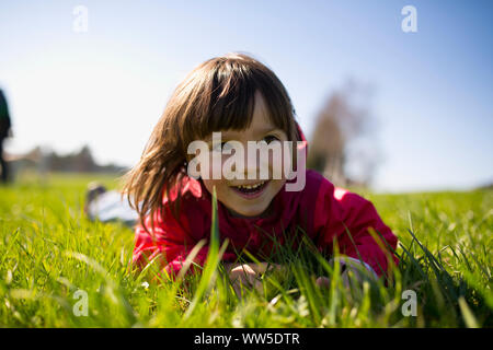 5-year-old girl with red jacket sur un pré vert Banque D'Images