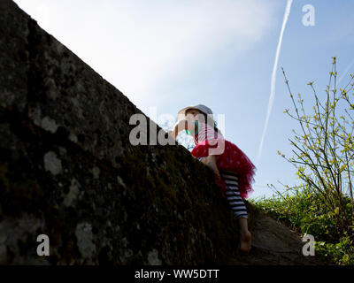 5-year-old fille en robe rayée sur le mur d'escalade Banque D'Images