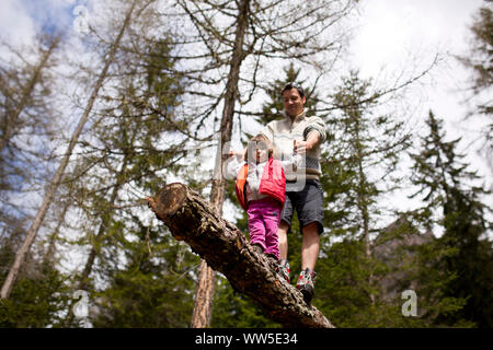 30-40 ans père balancingon un tronc dans la forêt avec sa fille âgée de 4 à 6 ans Banque D'Images