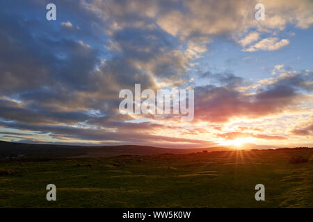 Le coucher du soleil et ciel dramatique sur les terres agricoles à un lointain cow silhouette sur le ciel rouge. Banque D'Images