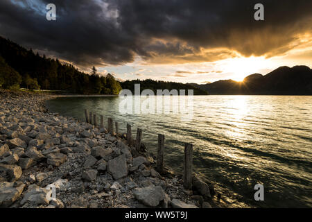 Beaux nuages pendant le coucher du soleil à Le Walchensee dans les Préalpes bavaroises, remblai, des pierres et des poteaux en bois Banque D'Images