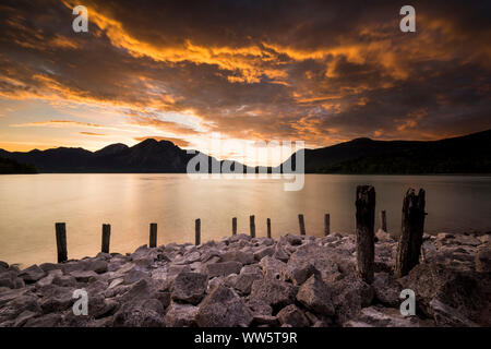 Beaux nuages pendant le coucher du soleil à Le Walchensee dans les Préalpes bavaroises, remblai, des pierres et des poteaux en bois Banque D'Images