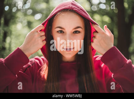 Jeune femme athlète attrayant in hoodie sur avant que l'activité dans les bois. Portrait de femme de race blanche sports vêtements rose redresser Banque D'Images