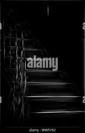 Lumière sur l'escalier étroit d'un couloir sombre avec des marches de bois. Banque D'Images