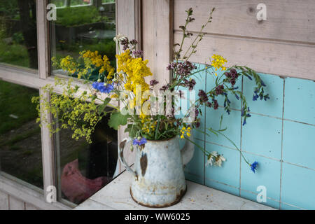 Bouquet mélangé coloré de fleurs sauvages d'été cinglante en métal rouillé cafetière sur le comptoir contre mur carrelé aqua Banque D'Images