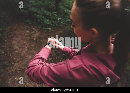 Top Vue d'une fille sportive remise en forme de bracelet sur la formation dans la forêt. Smart watch sur une fille sportive poignet. Smart watch, coeur en santé Banque D'Images