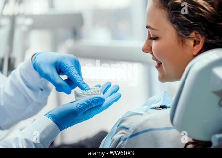 Male dentist montrant sa femme comment brosser les dents correctement, l'utilisation du moule. Femme mature en regardant son dentiste expliquant à propos de dents et Banque D'Images