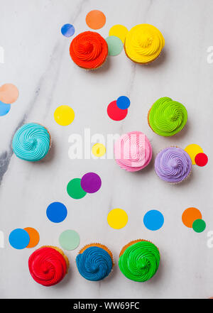 Cupcakes colorés sur la mise à plat en arrière-plan avec copie espace. Style pop art avec rainbow circles confetti Banque D'Images