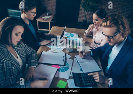 Quatre belles attrayant beau élégant chic smart intelligent requins d'affaires axée sur le calcul de la rédaction de notes d'experts rapport de données du schéma de modern Banque D'Images