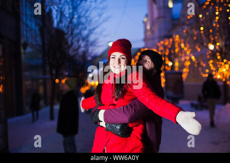 Portrait de jolie femme souriante avec son mari debout derrière, en tenant son étreinte. Visage de femme éclairée par une lampe de poche, d'une ville le soir avec Banque D'Images